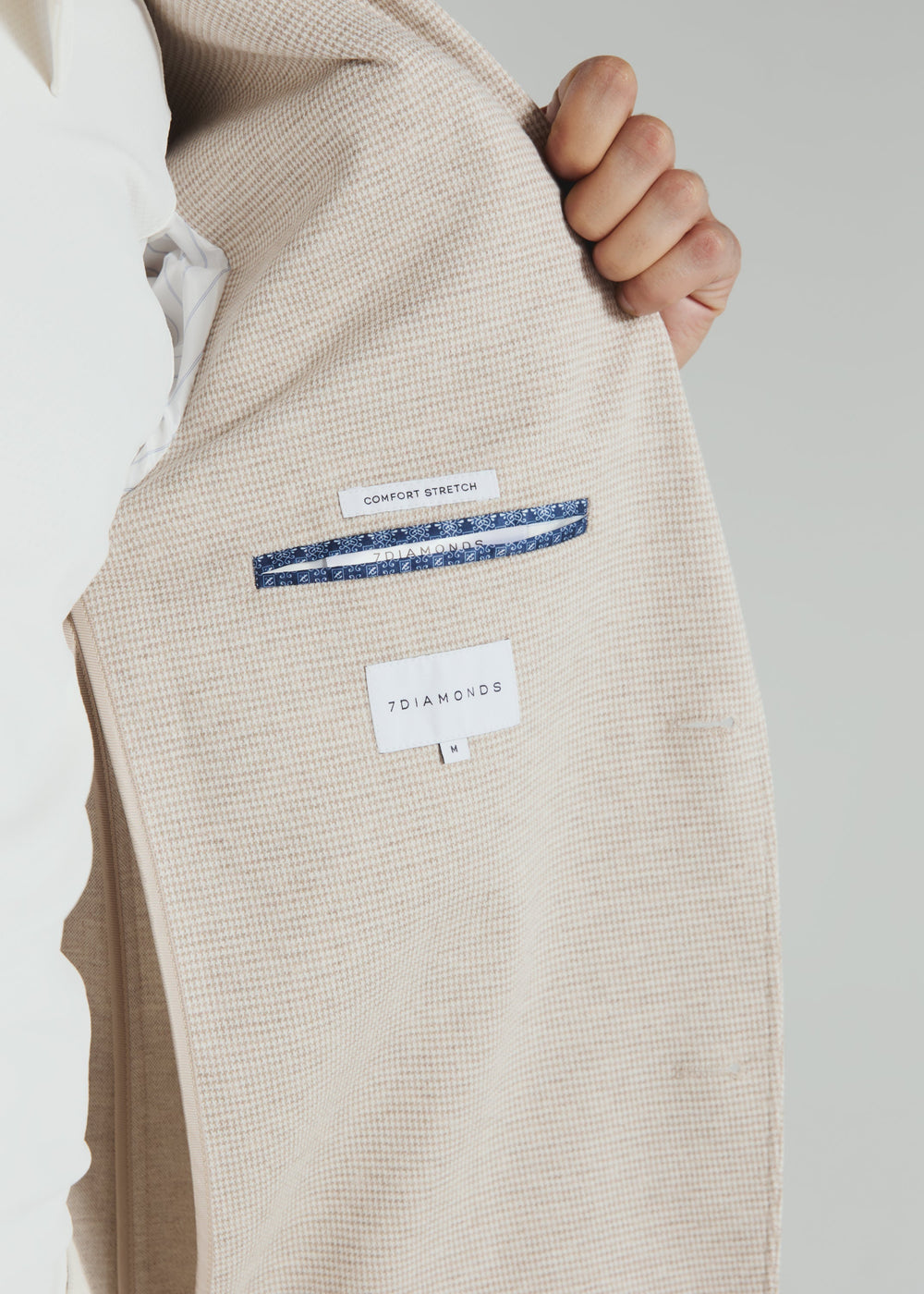 Beige textured fabric with a brand label on a neutral background